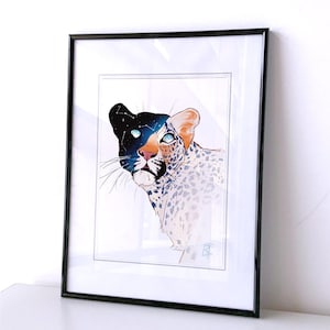 May include: A framed print of a black and white leopard with a galaxy pattern on its head. The leopard's eyes are blue and the galaxy pattern is made up of stars and constellations. The print is on a white background and is framed in a black frame.