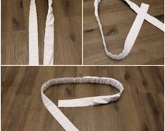 May include: White fabric belt with a gathered design and two snap closures. The belt is shown in three different positions.