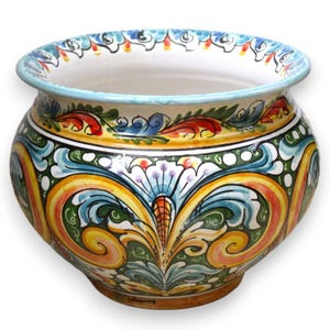 Può includere: Un vaso in ceramica rotondo caratterizzato da un design dipinto a mano con motivi a volute nei colori giallo, verde, blu e rosso. Il contenitore a bocca larga presenta un interno bianco e un bordo svasato decorato con un motivo blu e bianco.