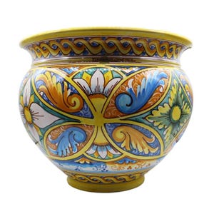Peut inclure: Un pot de fleurs en céramique rond orné d'un motif peint à la main aux tons jaunes, bleus et orange, représentant des fleurs et des volutes. Le bord et la base présentent une bordure jaune en forme de corde et des panneaux géométriques.