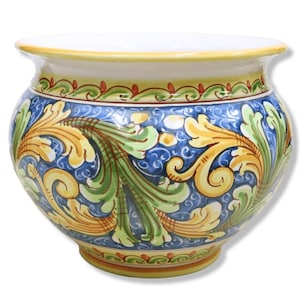 Puede incluir: Una maceta de cerámica con una forma ancha y redondeada. La maceta presenta un interior blanco, un borde amarillo y un exterior azul adornado con motivos florales amarillos y verdes. La base tiene un pie pequeño y el diseño es ornamentado.