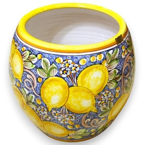 Può includere: Una ciotola in ceramica con bordo giallo ed esterno blu decorata con limoni gialli, foglie verdi e fiori bianchi. La ciotola ha una forma rotonda e una superficie liscia. Il disegno è dipinto a mano.