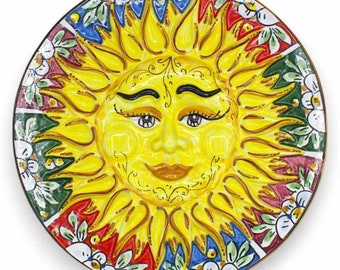 May include: A yellow ceramic plate featuring a painted sun face and floral designs in red, blue, green, and white.
