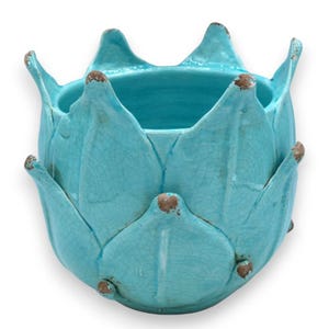 May include: A turquoise ceramic planter shaped like an artichoke or lotus flower. The vessel features a glossy crackle glaze finish with brown, distressed-looking tips on each petal-like protrusion, creating a textured appearance throughout.
