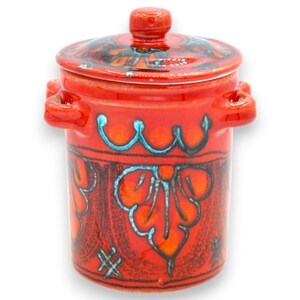 Puede incluir: Un recipiente de cerámica de color naranja brillante con tapa a juego y dos asas laterales. El exterior presenta un patrón floral pintado a mano en rojo oscuro y azul turquesa con líneas festoneadas y detalles de trama cruzada en la base.
