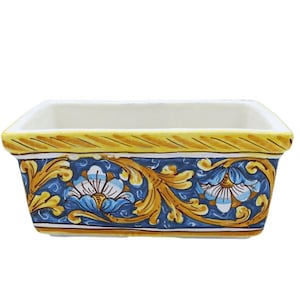 Può includere: Piatto rettangolare in ceramica con interno bianco e bordo giallo. L'esterno presenta uno sfondo blu con motivi floreali e di foglie in oro e bianco. Il piatto è probabilmente per scopi decorativi o di servizio.
