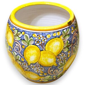 Peut inclure: Un cache-pot en céramique rond orné d'un motif peint à la main représentant des citrons jaune vif, des feuilles vertes et de petites fleurs blanches sur un fond bleu tourbillonnant. Le bord présente une bande jaune unie et un intérieur blanc.