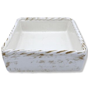 May include: A square, white ceramic dish with a textured, rope-like border. The dish has a distressed, rustic appearance with subtle brown accents on the edges, creating a vintage aesthetic. The interior is smooth and bright white.