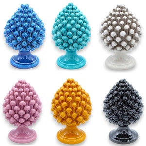 以下が含まれることがあります： 青、ターコイズ、白、ピンク、黄、黒など、さまざまな色のセラミック製の松ぼっくり彫刻6個。各松ぼっくりは、個々の鱗で詳細に作られており、台座の上に置かれています。