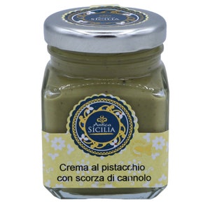 May include: A glass jar with a silver lid filled with green pistachio cream. The jar has a yellow label with the text "Antica Sicilia" and "Crema al pistacchio con scorza di cannolo".