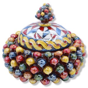 Peut inclure: Un pot en céramique rond avec couvercle, doté d'un extérieur texturé recouvert de petites sphères brillantes et multicolores dans des tons de rouge, jaune et bleu. Le couvercle présente un motif géométrique en étoile et une poignée en grappe.