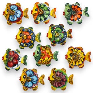 May include: A collection of ten ceramic fish figurines, each featuring hand-painted floral patterns in vibrant colors including red, yellow, blue, green, and orange. The fish are arranged in a grid, displaying various circular shapes and fins.