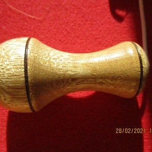 May include: A wooden knob with a dark brown line around the centre. The knob is light brown and has a smooth, slightly textured surface.