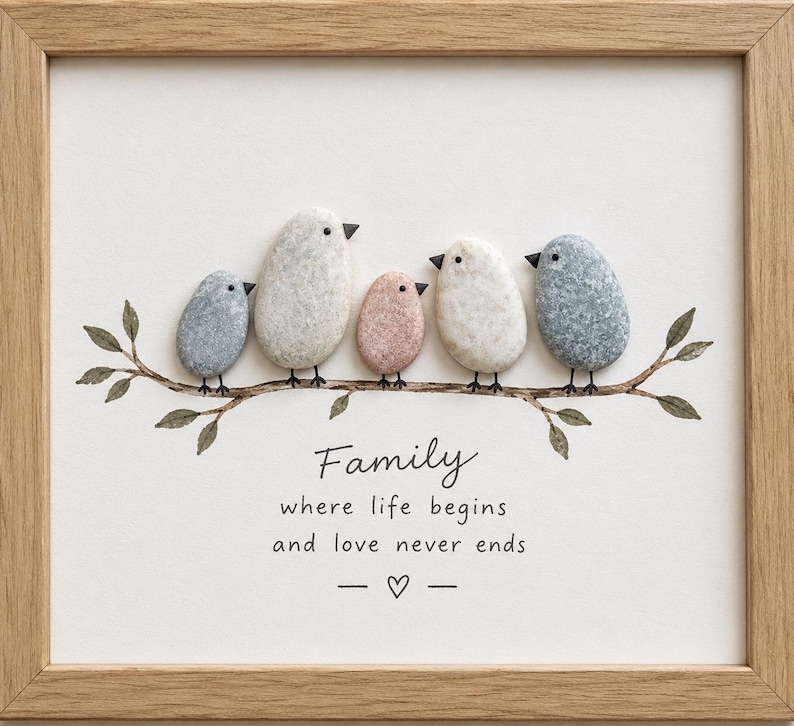May include: A framed pebble art piece featuring five birds made of smooth stones perched on a painted branch. The text reads: Family where life begins and love never ends, with a small heart symbol below. The frame is light wood.