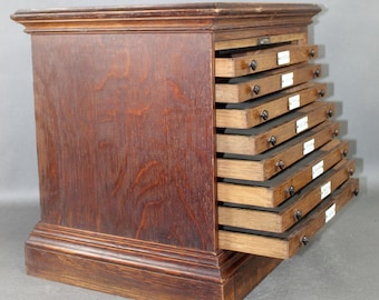 Könnte beinhalten: Ein dunkles Holzkabinett mit acht Schubladen, jede mit einem kleinen Metallgriff. Die Schubladen sind geöffnet und zeigen das Innere des Schranks.