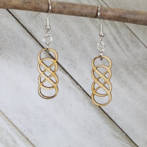 May include: A pair of wooden earrings featuring a Celtic knot design. The earrings are made from light brown wood and have silver hooks.
