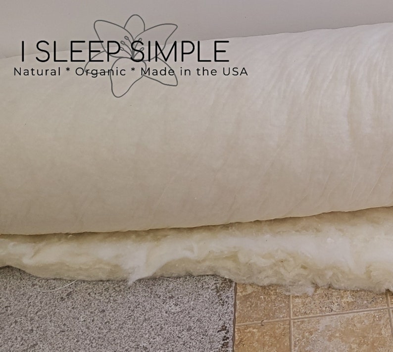 May include: A white, rolled-up, organic cotton mattress topper with the text "I SLEEP SIMPLE Natural * Organic * Made in the USA" printed on the top.
