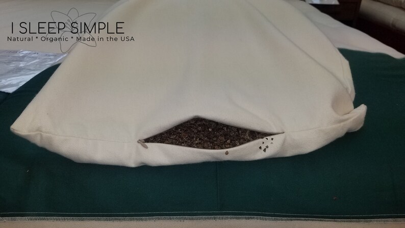 Peut inclure: Une taie d'oreiller blanche avec le texte "I SLEEP SIMPLE Natural * Organic * Made in the USA" est ouverte pour r&eacute;v&eacute;ler un garnissage d'oreiller en coque de sarrasin brun.