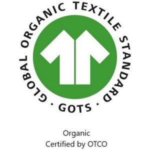 May include: Green circle with the text "GLOBAL ORGANIC TEXTILE STANDARD GOTS" around the outside. Inside the circle is a white silhouette of two t-shirts facing each other. Below the circle is the text "Organic Certified by OTCO OT-024293".