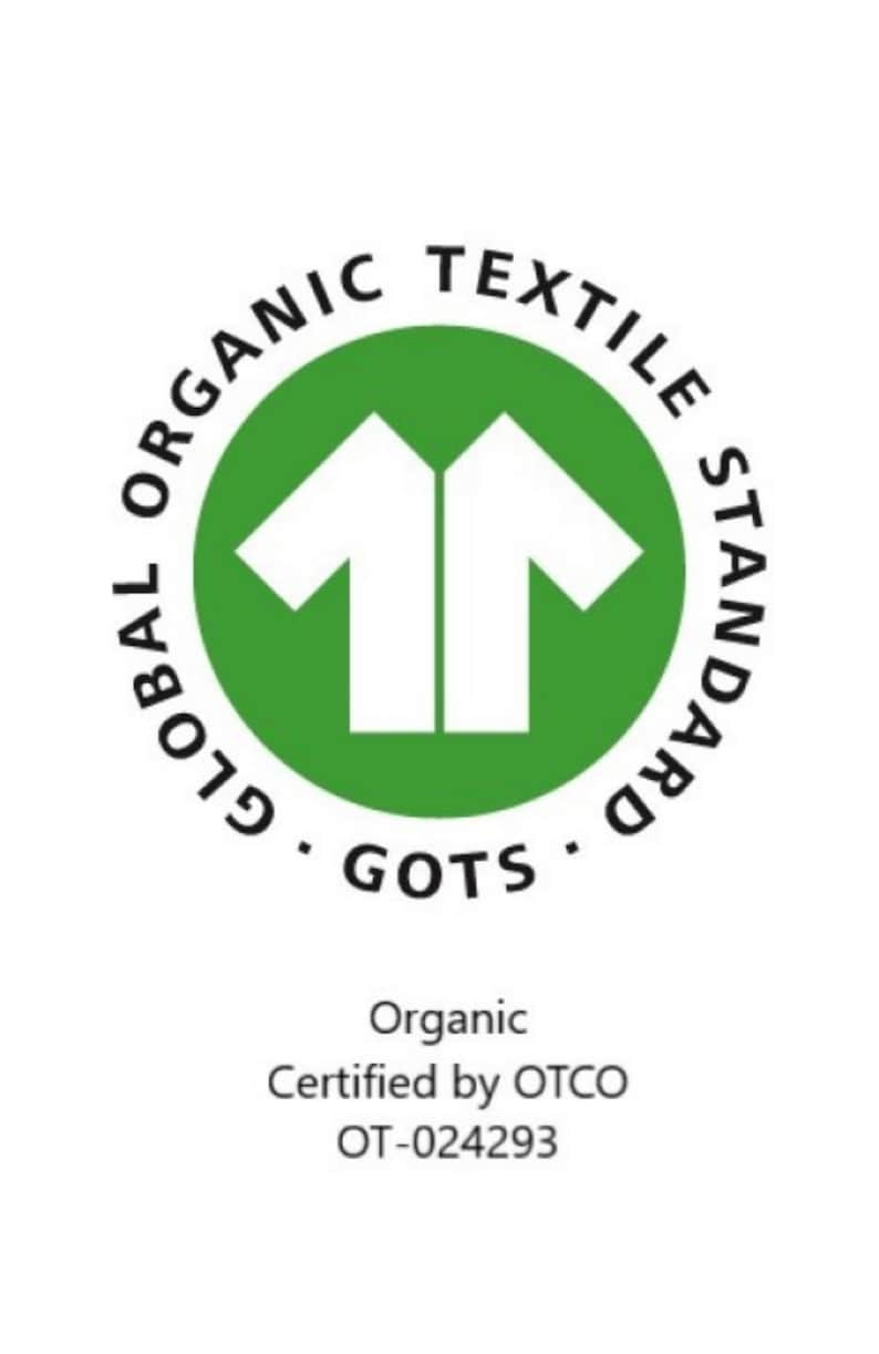 May include: Green circle with the text "GLOBAL ORGANIC TEXTILE STANDARD GOTS" around the outside. Inside the circle is a white silhouette of two t-shirts facing each other. Below the circle is the text "Organic Certified by OTCO OT-024293".