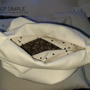 Peut inclure: Un oreiller en coton blanc avec une fermeture &eacute;clair est rempli de coques de sarrasin. L'oreiller est ouvert et les coques sont visibles. Le texte "I SLEEP SIMPLE" est imprim&eacute; sur l'oreiller. Le texte "Natural * Organic * Made in the USA" est imprim&eacute; sous le nom de l'entreprise.