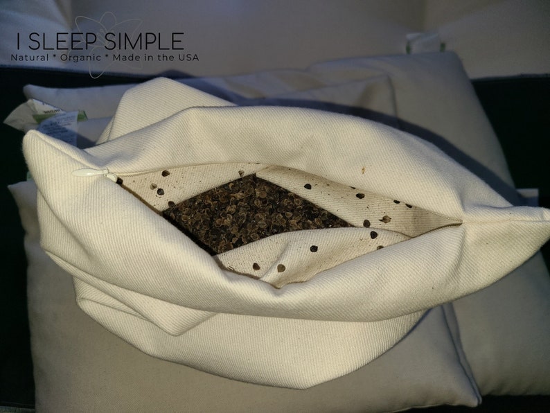 Peut inclure: Un oreiller en coton blanc avec une fermeture &eacute;clair est rempli de coques de sarrasin. L'oreiller est ouvert et les coques sont visibles. Le texte "I SLEEP SIMPLE" est imprim&eacute; sur l'oreiller. Le texte "Natural * Organic * Made in the USA" est imprim&eacute; sous le nom de l'entreprise.