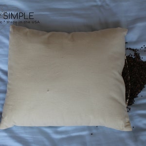 Peut inclure: Une taie d'oreiller blanche avec une fermeture &eacute;clair, remplie de coques de sarrasin. La taie d'oreiller est sur un drap bleu avec des coques de sarrasin &eacute;parpill&eacute;es autour. Le texte "I SLEEP SIMPLE" est imprim&eacute; sur le drap. Le texte "Natural * Organic * Made in the USA" est imprim&eacute; sous le nom de l'entreprise.