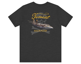 May include: A dark heather gray short-sleeve t-shirt featuring a graphic on the back. The design displays a fighter jet, a skull silhouette, and the text "Tomcat" in yellow script, with "Aces In Action Historical Gallery" printed below.