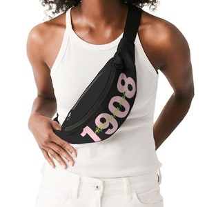 May include: A black fanny pack with a pink 1908 design. The fanny pack is worn across the body.