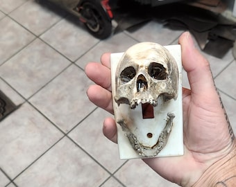 Mini hard plastic skull lightswitch. Very good detail. Comes in white when shipped . You can paint it any color you would like to match.