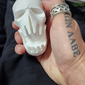 May include: A white, 3D-printed skull figurine with detailed facial features, held in a hand. The skull has a wide open mouth and eye sockets. The image includes the text "This is my life. June 02, 2025 6:16 PM."