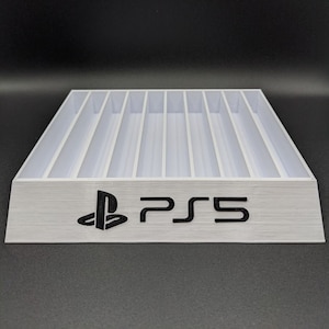 May include: White plastic game case with slots for storing video game discs. The case has a PlayStation logo and the text "PS5" printed on the front.