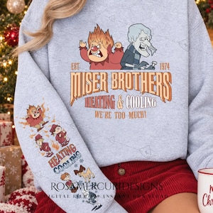 Pode incluir: Uma camisola cinzenta clara de gola redonda com um gráfico dos irmãos Miser e o texto "EST 1974 MISER BROTHERS HEATING & COOLING WE'RE TOO MUCH!". A manga apresenta uma sequência vertical de ilustrações de personagens e as palavras "HEATING COOLING".