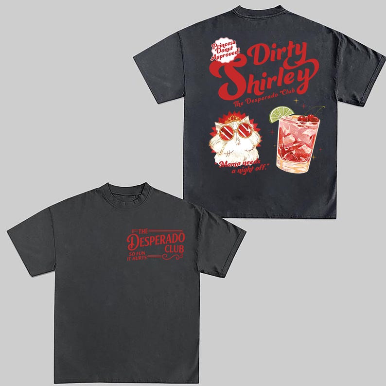 May include: Two dark gray t-shirts. One features the text "The Desperado Club" in red. The other shirt has a graphic of a cocktail and a cat wearing sunglasses, with the text "Dirty Shirley" and "Mama needs a night off."