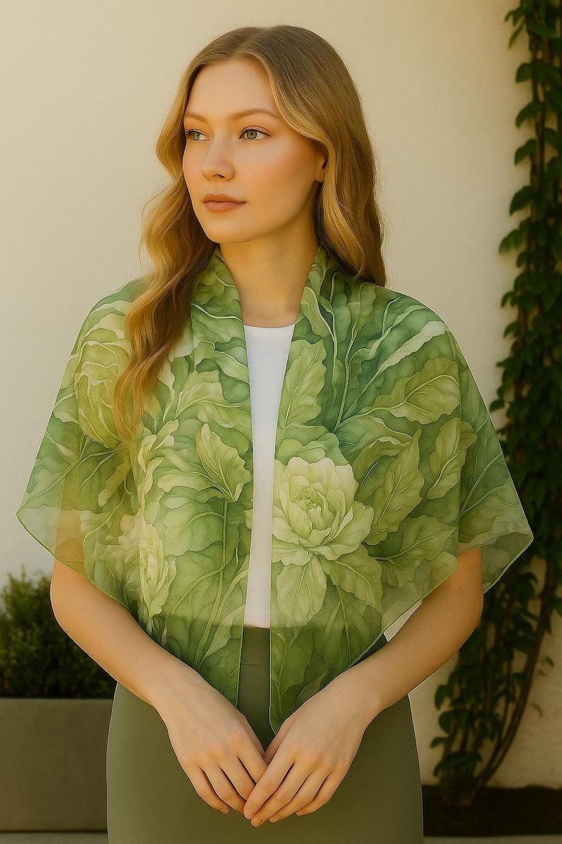 May include: A green silk scarf with a floral pattern. The scarf is draped around a person's neck and shoulders.
