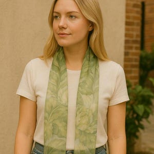 May include: A woman wearing a white t-shirt and blue jeans with a green floral scarf around her neck.