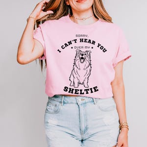 Peut inclure: T-shirt rose avec un graphique noir d'un chien Sheltie et le texte "D&eacute;sol&eacute;, je ne t'entends pas &agrave; cause de mon Sheltie".