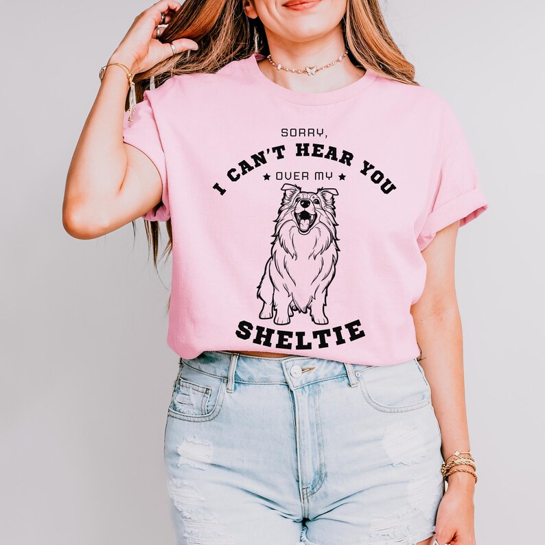 Peut inclure: T-shirt rose avec un graphique noir d'un chien Sheltie et le texte "D&eacute;sol&eacute;, je ne t'entends pas &agrave; cause de mon Sheltie".