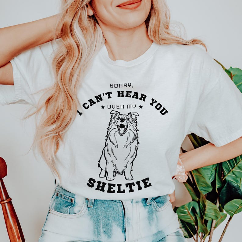 Peut inclure: T-shirt blanc avec un graphique noir d'un chien Shetland et le texte "D&eacute;sol&eacute;, je n'entends pas au-dessus de mon Shetland".