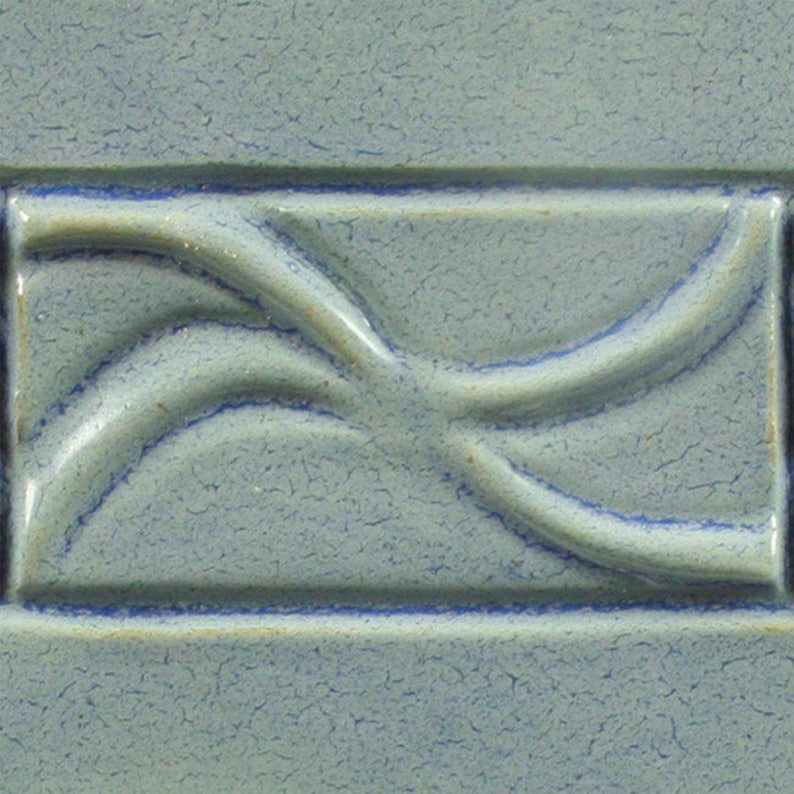May include: A light blue ceramic tile with a raised design of a stylised swirl pattern.