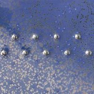 Pu&ograve; includere: Primo piano di un piatto in ceramica blu con una superficie testurizzata e punti argentati.