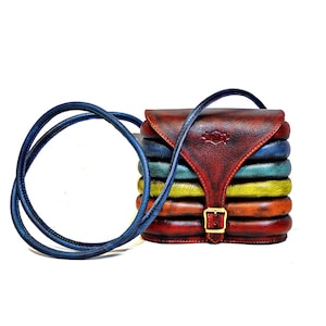 May include: A small, multi-coloured leather crossbody bag with a flap closure and a buckle. The bag is made of stacked leather panels in shades of brown, red, yellow, and blue.