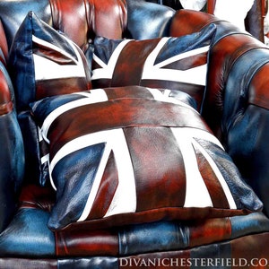 May include: A leather armchair with a Union Jack design on the cushions. The chair is a mix of blue, red, and brown leather, with brass-colored nailhead trim. The cushions feature a white and red Union Jack flag.
