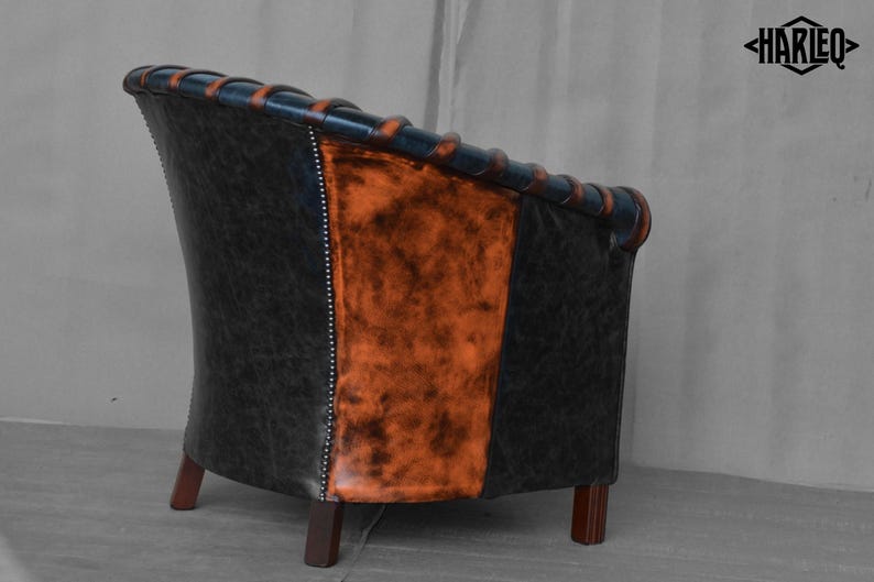 May include: A black and orange leather armchair with a tufted back and wooden legs. The chair is angled to show the side view.