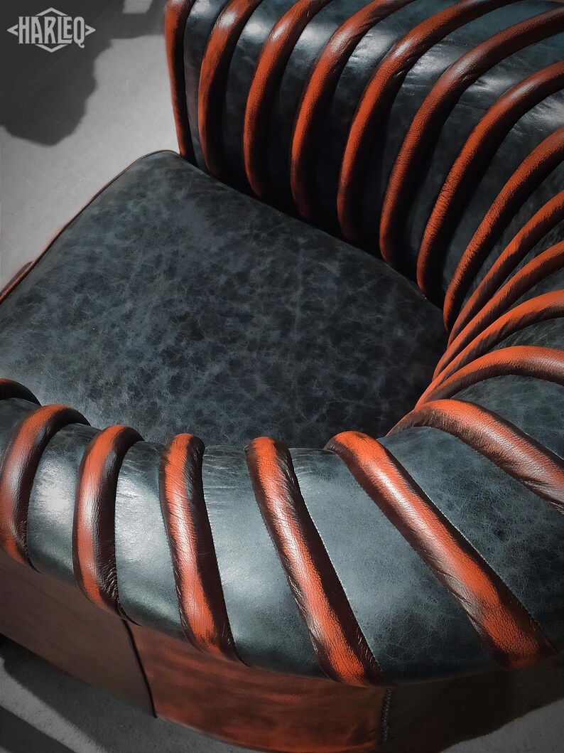 May include: A black leather armchair with orange leather piping. The chair has a unique design with the piping forming a spiral pattern.