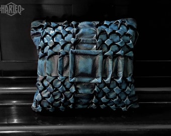 May include: A blue leather pillow with a quilted design and a large buckle in the center.