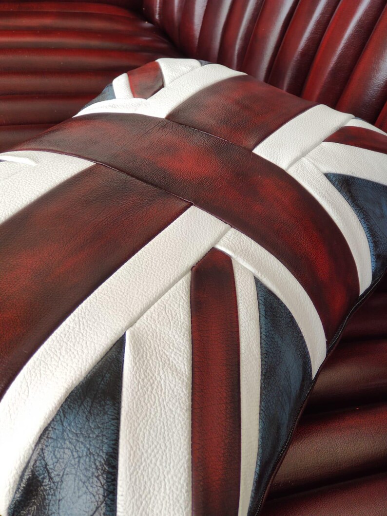 Pu&ograve; includere: Un cuscino decorativo con il design della Union Jack, nei colori bordeaux, bianco e blu navy. Il cuscino &egrave; realizzato in un materiale strutturato ed &egrave; posto su una superficie bordeaux. Il design &egrave; audace.