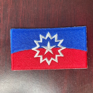Puede incluir: Un parche bordado azul y rojo con un diseño de estrella blanca. La estrella tiene 16 puntas y una estrella blanca en el centro.