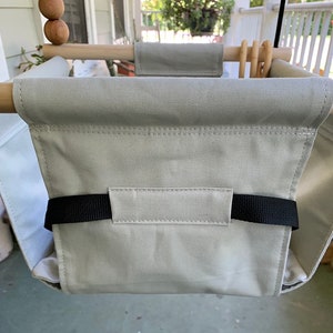 May include: A gray canvas swing seat with black straps. The swing is hanging from a wooden frame.