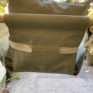 May include: A beige canvas swing seat with a padded back and a strap across the front. The swing is hanging from a wooden frame.